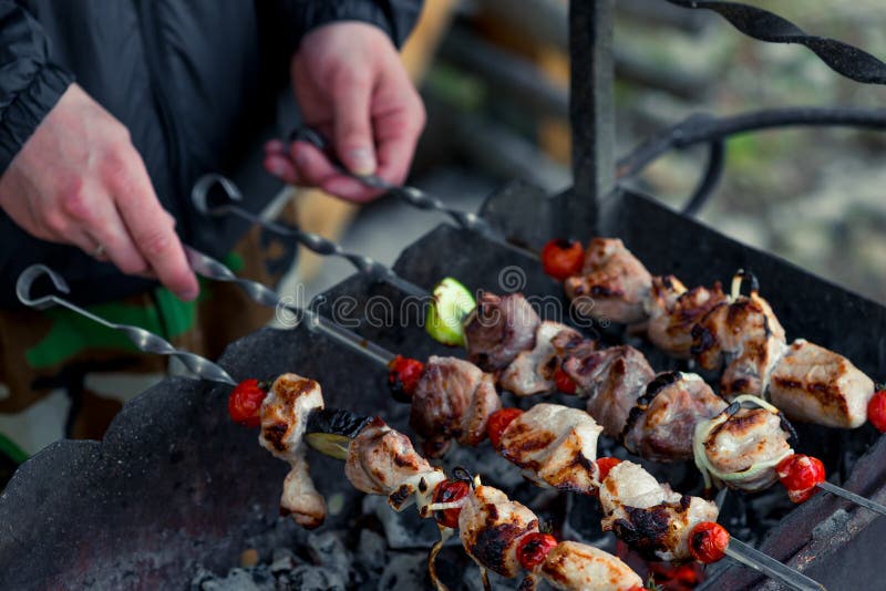 Male hand with shish kebab skewers on the grill stock photography Male hand with shish kebab skewers on the grill stock photography