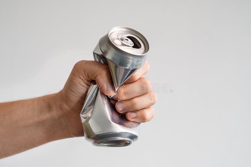 male hand squeezes an empty aluminum can for recycling. expression of anger and powerlessness.