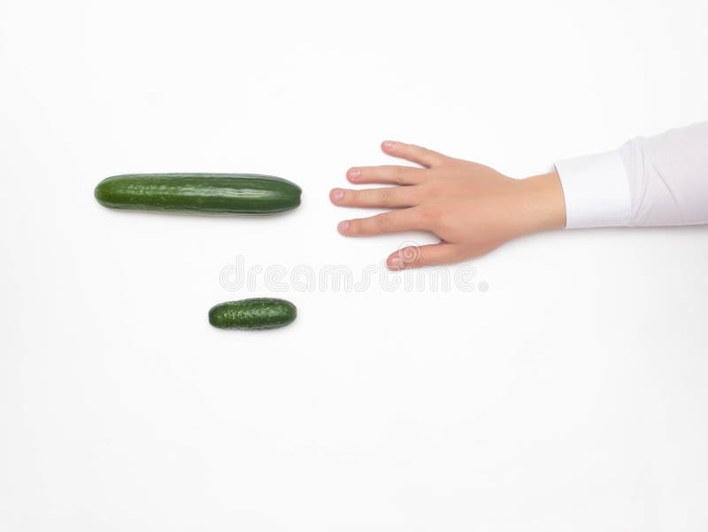 Male hand on a white background reaching for a big cucumber, the concept of increasing the male penis using different stock image