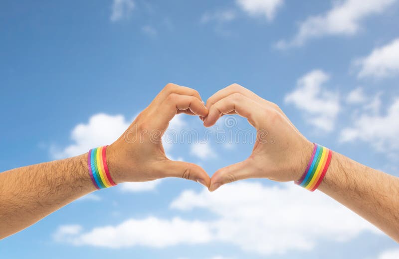 Male hands with gay pride wristbands showing heart