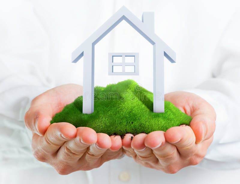 Male hands holding a green hill with a small house