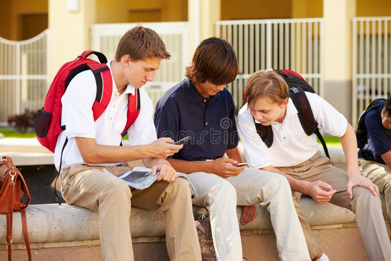Male High School Students Using Mobile Phones On School Campus