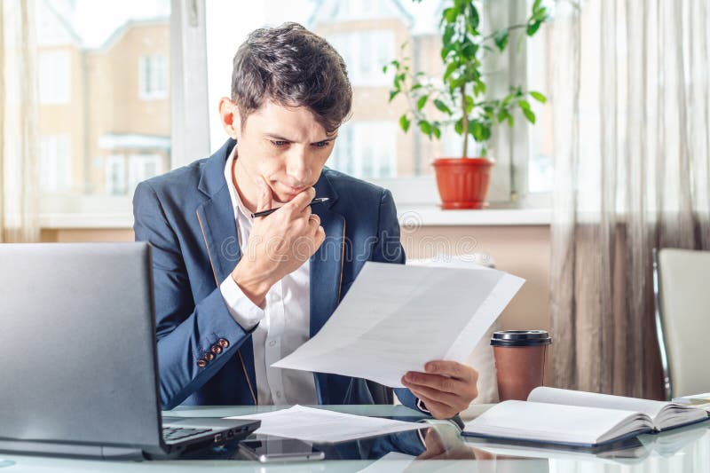 Male Lawyer Sitting at a Work Place Examing Documents. Concept of the