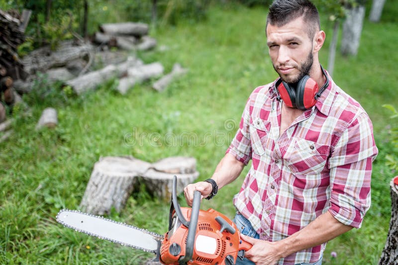 Male lumberjack with chainsaw cutting wood and timber stock photography Male lumberjack with chainsaw cutting wood and timber stock photography