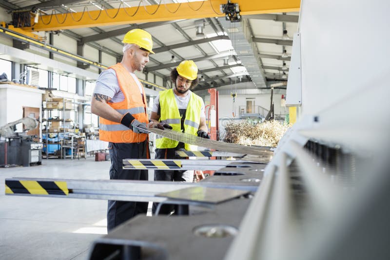 Male manual workers examining sheet metal at industry stock image Male manual workers examining sheet metal at industry stock image