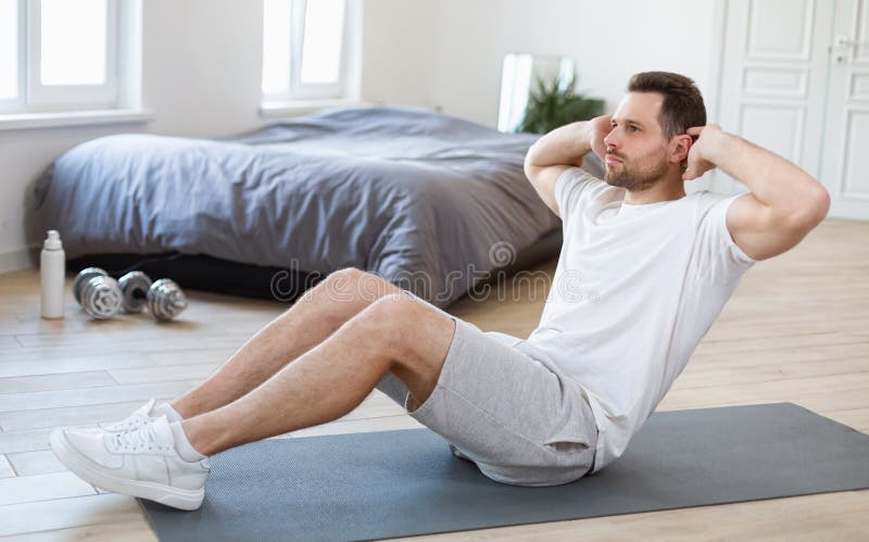 Home sport 1. Утренние упражнения на коврике. Мужчина занимается на коврике. Sport man sitting Home. Shutterstock Prostock-Studio.