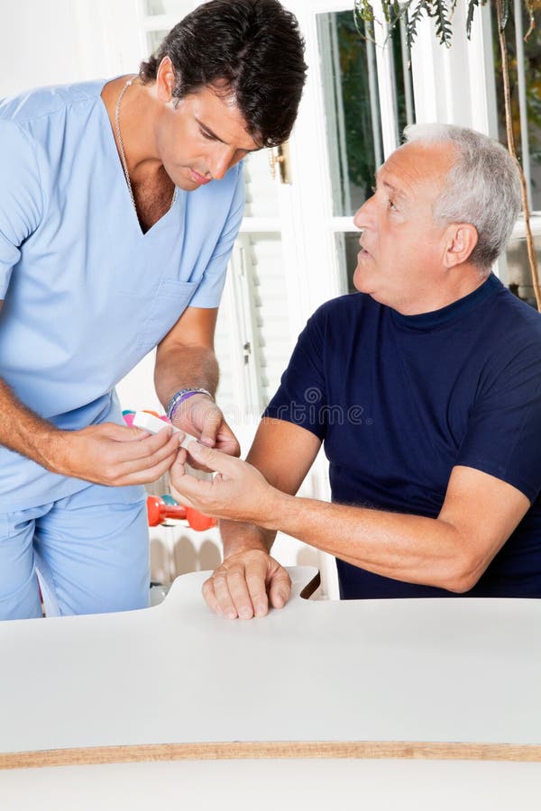 Male Nurse Checking Sugar Level Of Senior Man royalty free stock photo Male Nurse Checking Sugar Level Of Senior Man royalty free stock photo