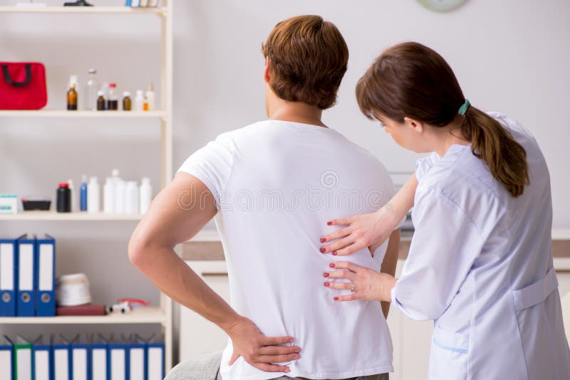 The male patient visiting young female doctor chiropractor