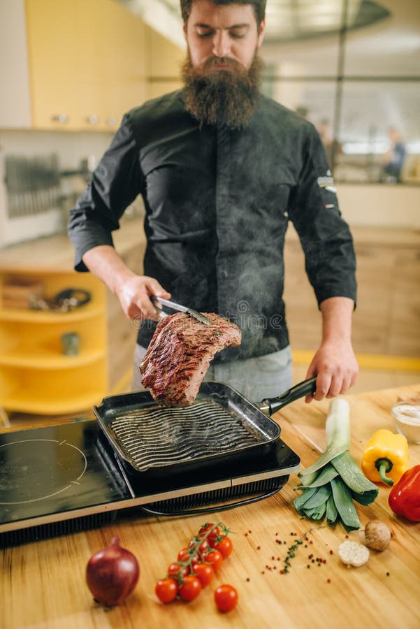 Bearded Chef Cooking Meat in a Pan on the Kitchen Stock Photo - Image ...