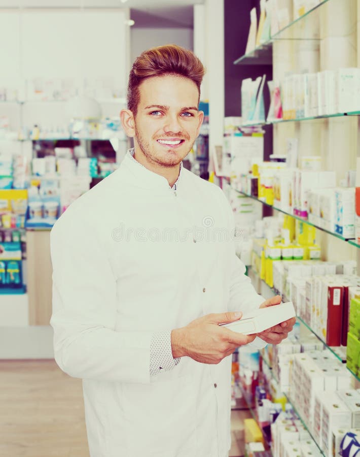 Male Pharmacist Wearing White Coat Standing In Drug Store Stock Image ...