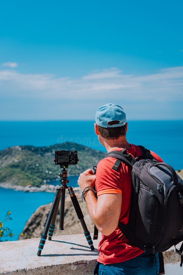 Male photographer with backpack enjoying view to Assos village during capture image from top view point. Camera on royalty free stock image Male photographer with backpack enjoying view to Assos village during capture image from top view point. Camera on royalty free stock image
