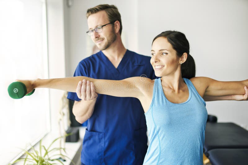 Male Physical Therapist Stretching a Female Patient Slowly. Stock Image