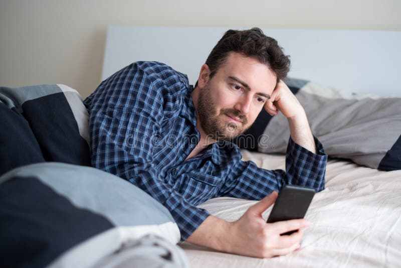 Male Portrait Watching Cellphone In The Bed Stock Photo