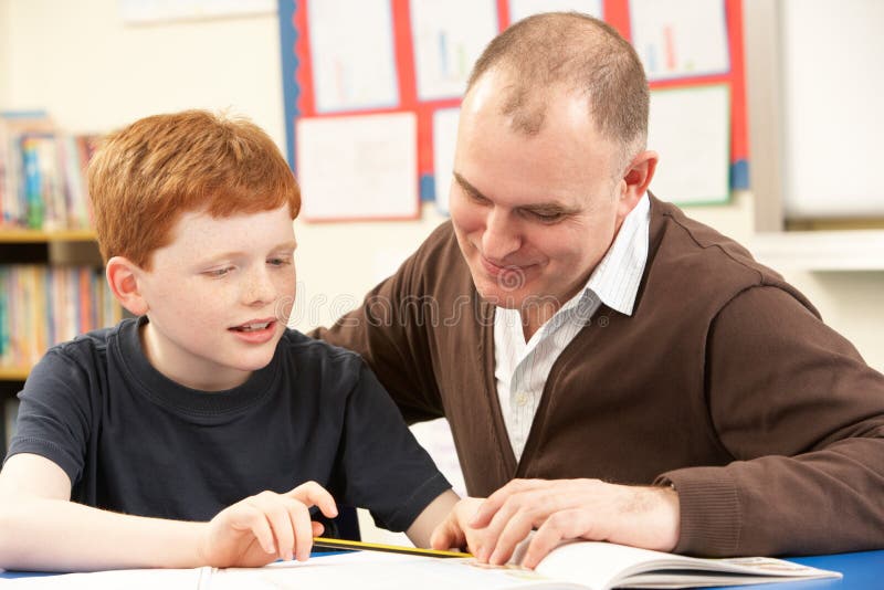 Male Pupil Studying in classroom with teacher Smiling