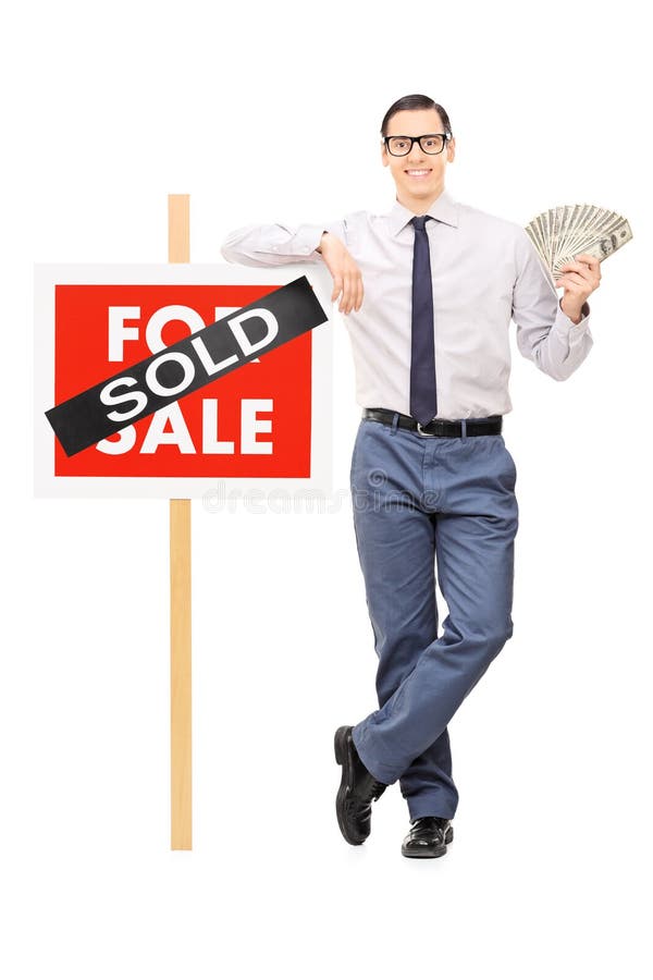 Male realtor holding money next to a sold sign isolated on white background