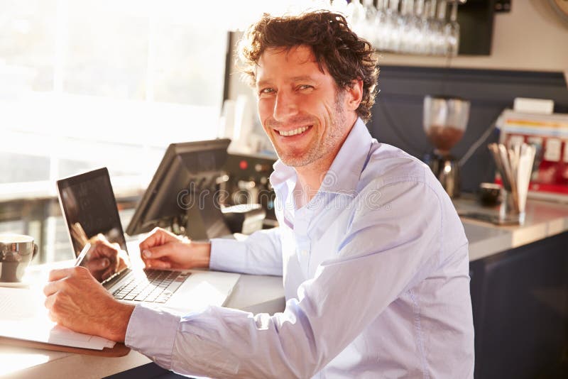 Male restaurant manager working on laptop stock photography