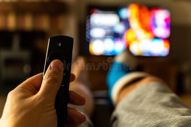 Male sat on sofa watching tv with a cast on foot from fifth metatarsal surgery, Shallow depth of field blured background..