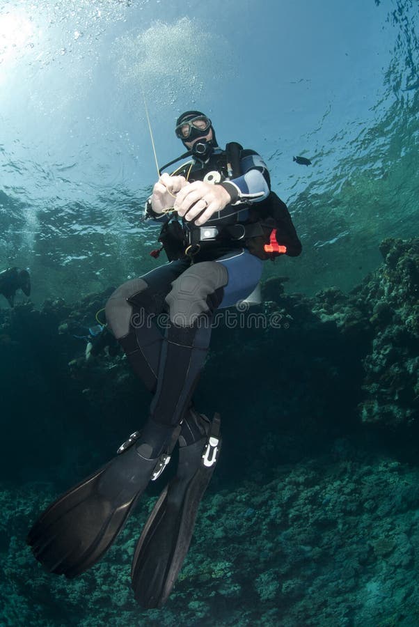 Male scuba diver holding a surface buoy.