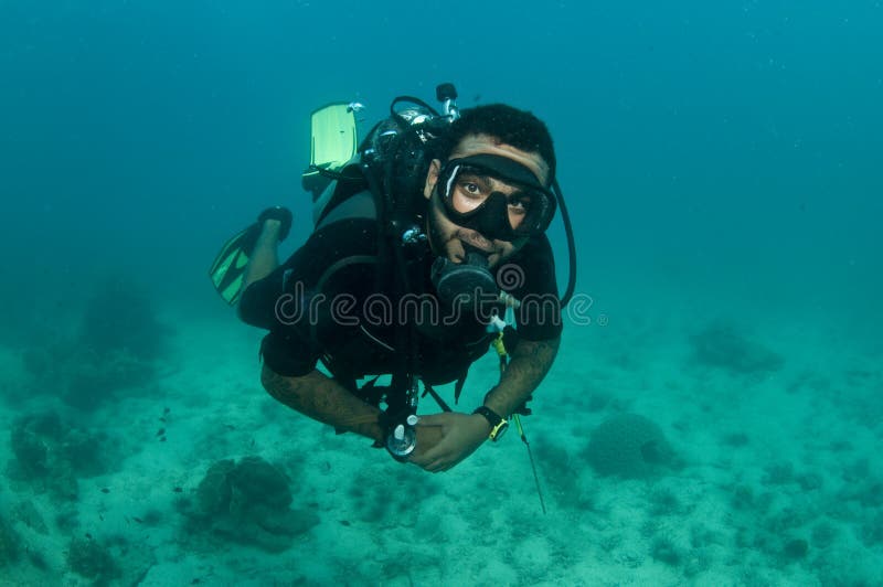 Male scuba diver swimming over reef