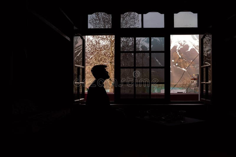 Male Sitting in the Darkroom with the Windows in the Background Stock