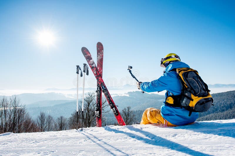 Male skier using selfie stick taking photos while skiing