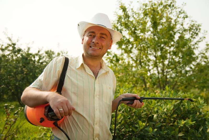 Working man with garden spray against summer time in garden. Working man with garden spray against summer time in garden