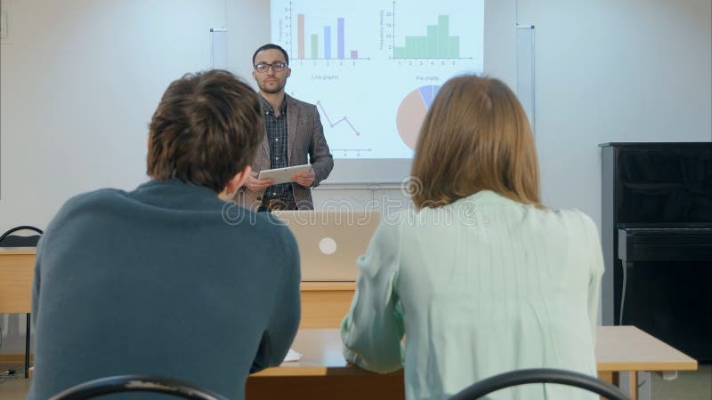 Male student raising hand and asking teacher a question sitting on table royalty free stock images Male student raising hand and asking teacher a question sitting on table royalty free stock images
