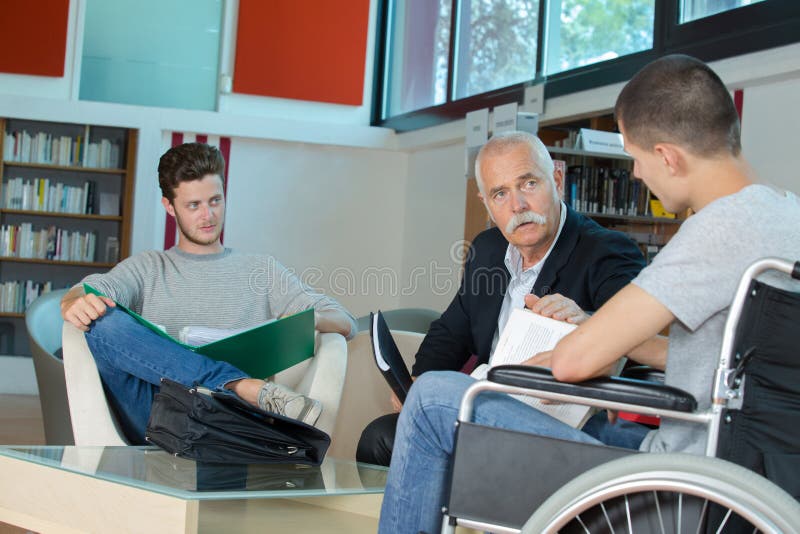 Male student in wheelchair at counter in college library stock images
