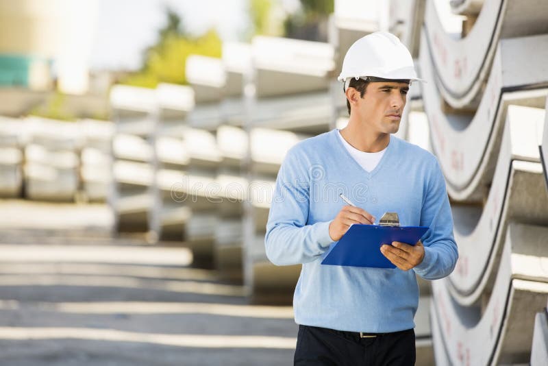 Male supervisor with clipboard inspecting stock at site stock image