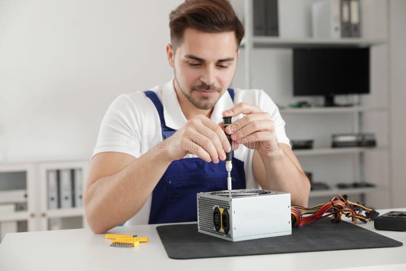 Male Technician Repairing Power Supply Unit at Table Stock Image