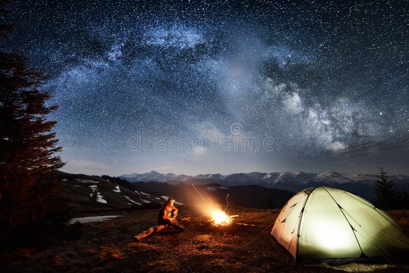 Male tourist enjoying in his camp near the forest at night under beautiful night sky full of stars and milky way royalty free stock images Male tourist enjoying in his camp near the forest at night under beautiful night sky full of stars and milky way royalty free stock images