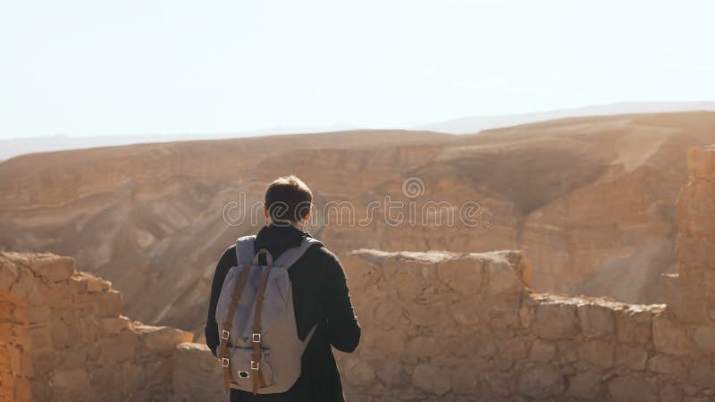 Male tourist photographs amazing mountain scenery. Young man with backpack takes photos. Freedom. Masada Israel 4K.