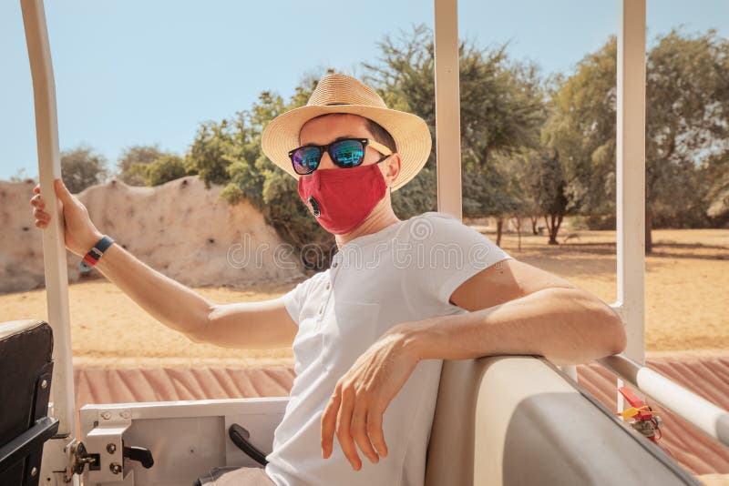 Male tourist wears a protective medical mask due to the coronavirus pandemic and rides in a car for a safari in the savannah or royalty free stock images