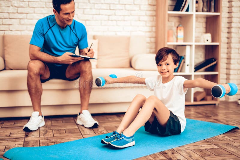 Male Trainer Looks at Boy with Dumbbells on Floor Stock Photo - Image ...