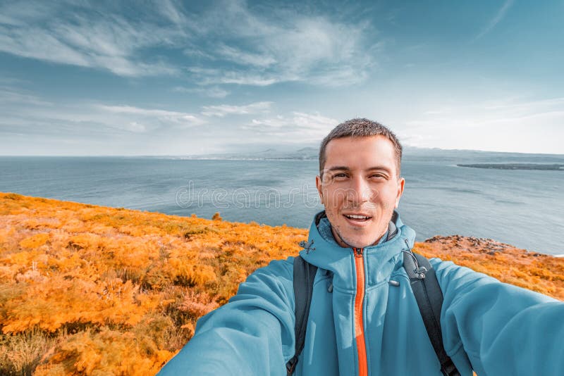 Male traveler takes a selfie against the background of Lake Sevan in Indian summer. Tourism in Armenia at autumn royalty free stock photo
