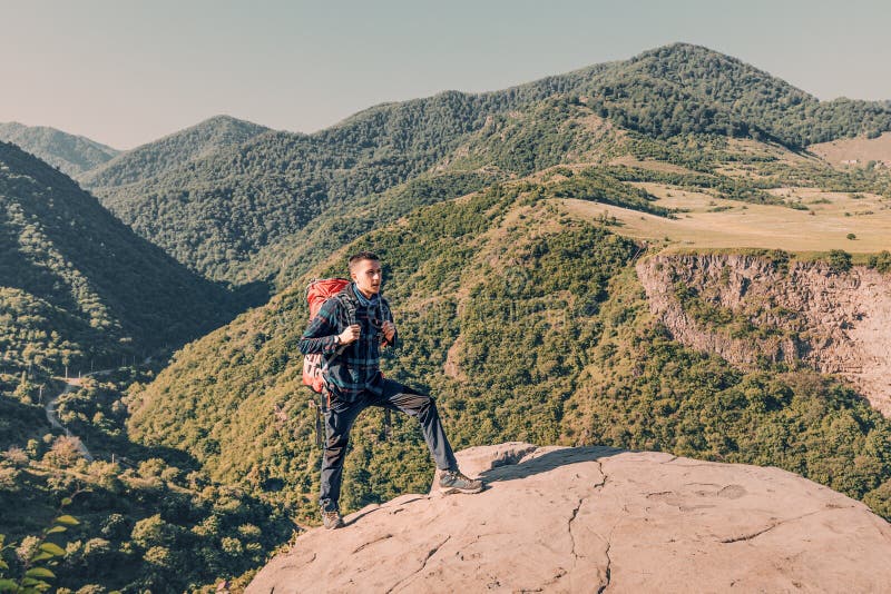 Male traveler with a trekking backpack climbs a rock in the mountains. Long distance trails and hike concept royalty free stock photo