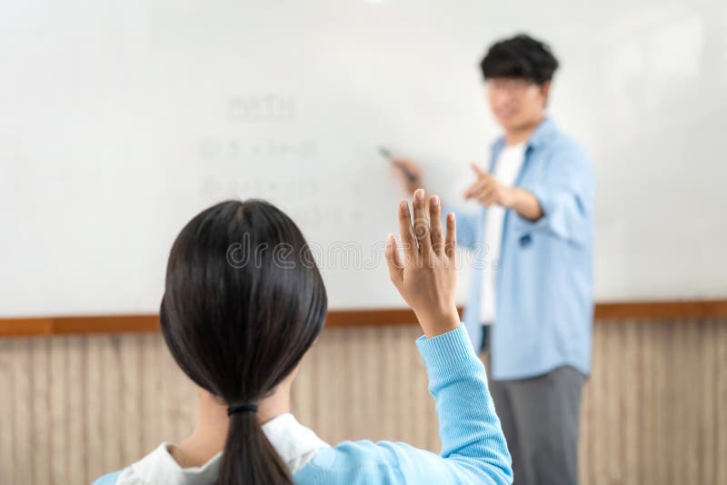 Male tutor standing in front of whiteboard is smiling and pointing to him for ask question and asian young boy royalty free stock photos
