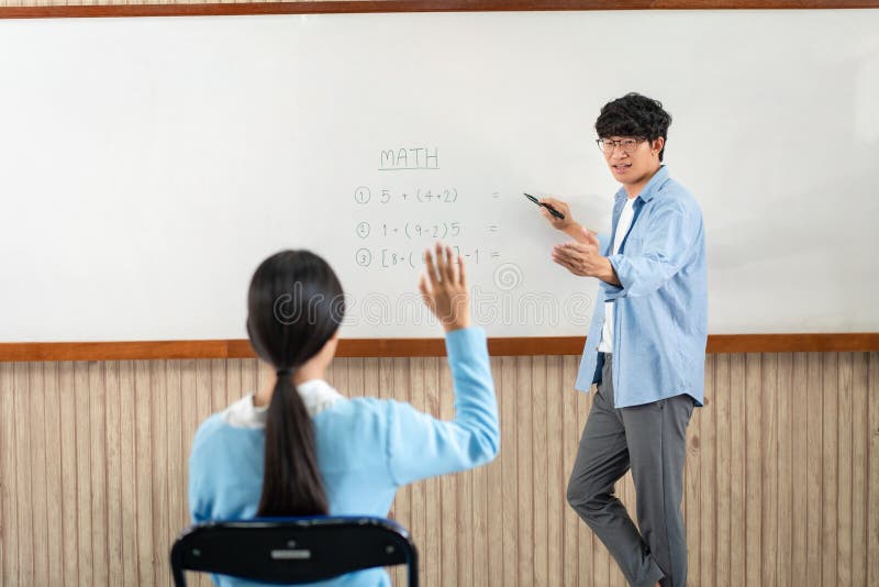 Male tutor standing in front of whiteboard is smiling and pointing to him for ask question and asian young boy royalty free stock photos