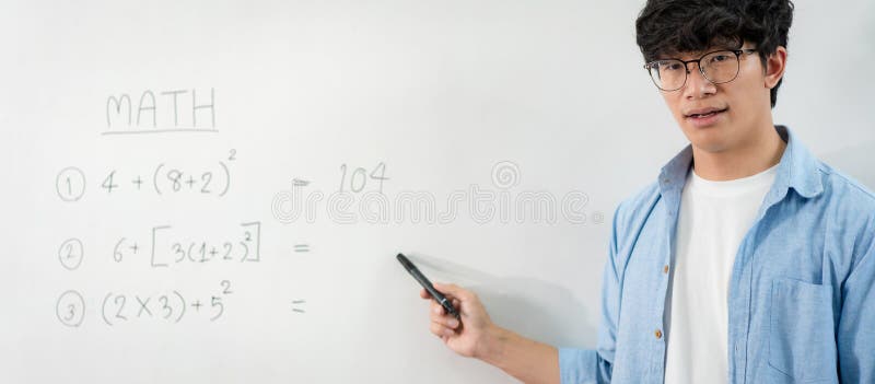 Male tutor standing in front of whiteboard and writing math equations on board to explaining new lesson royalty free stock image