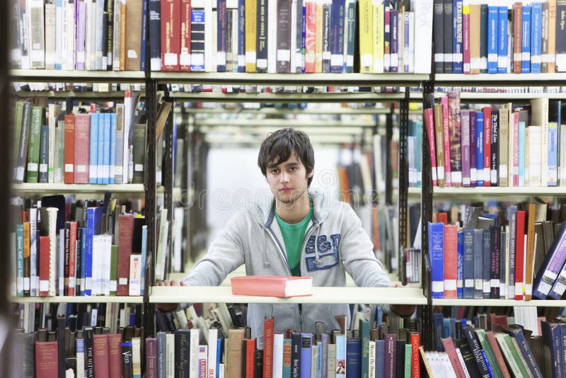 Ritratto giovane maschio università alunno nel mezzo libri biblioteca.