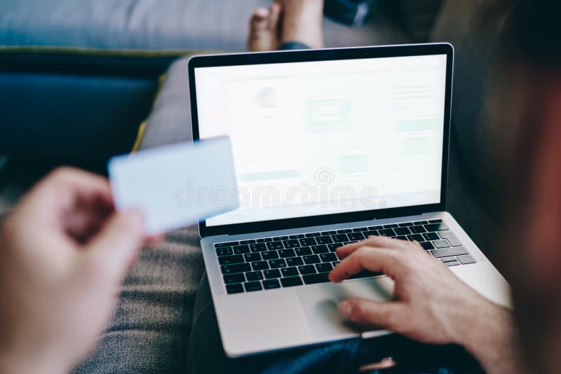 Back view of skilled man taking rest on couch and searching information about new web store in internet browser, male using 4g connection on laptop computer with blank screen area for advertising