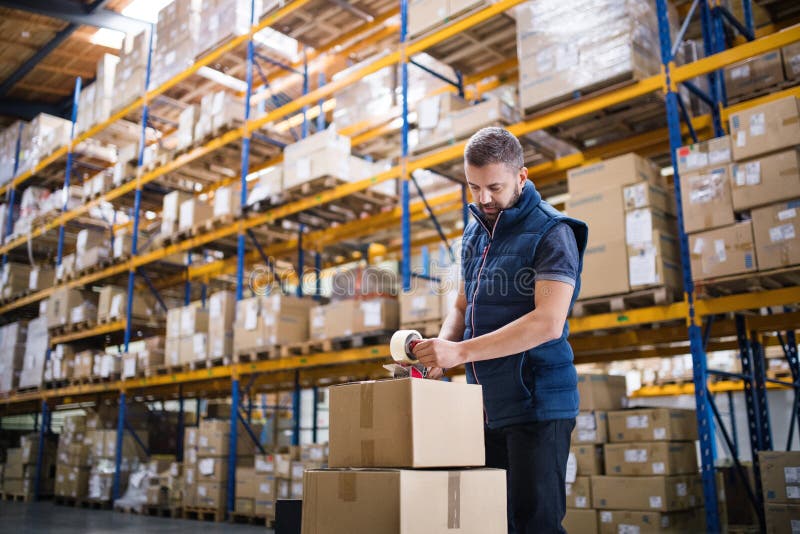 Male warehouse worker sealing cardboard boxes. royalty free stock photo