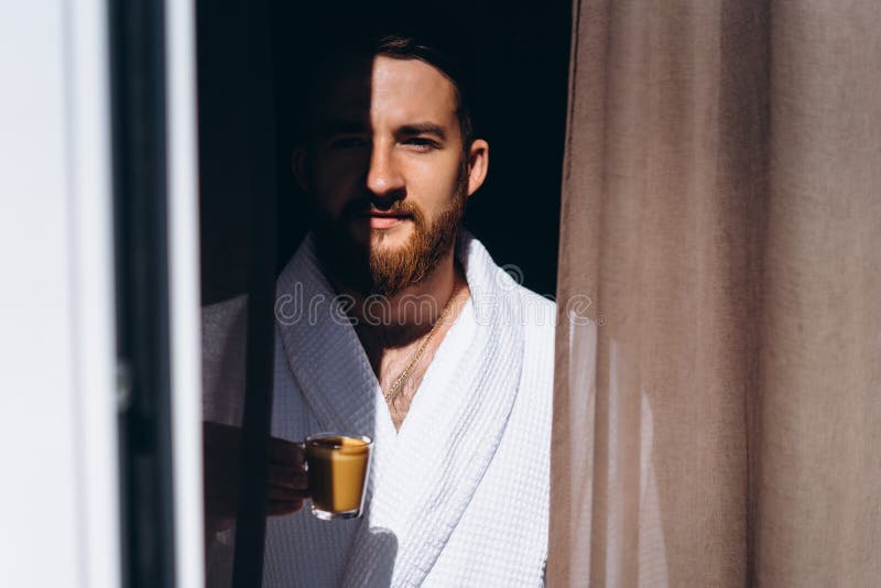 Male in White Bathrobe with Coffee Mug in Hand. Stock Photo Image of