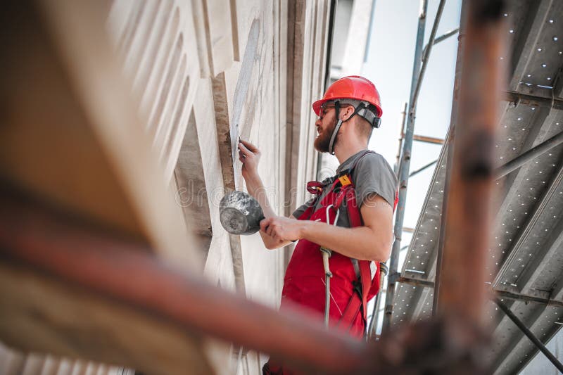 Male worker plastering old building wall using cement plaster mix