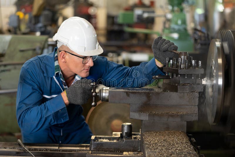 Male worker working on a lathe machine in metal industry factory on a business day