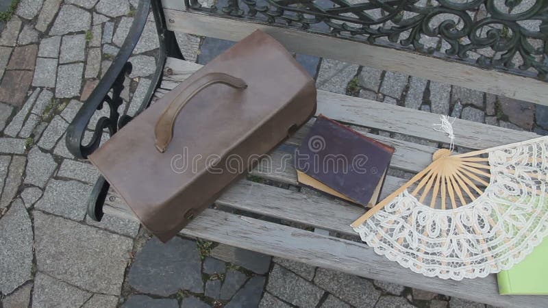 Maleta del vintage, libros y una fan en el banco almacen de metraje de vídeo Maleta del vintage, libros y una fan en el banco almacen de metraje de vídeo