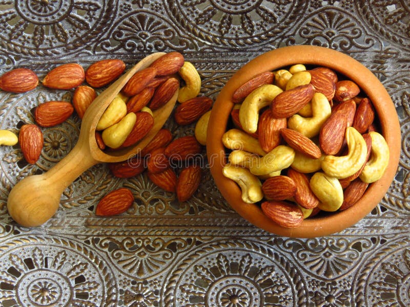 Malhas naturais torradas de amêndoa Badam e Cashew numa tigela feita de madeira e uma colher de madeira sobre elementos orientais foto de stock Malhas naturais torradas de amêndoa Badam e Cashew numa tigela feita de madeira e uma colher de madeira sobre elementos orientais foto de stock