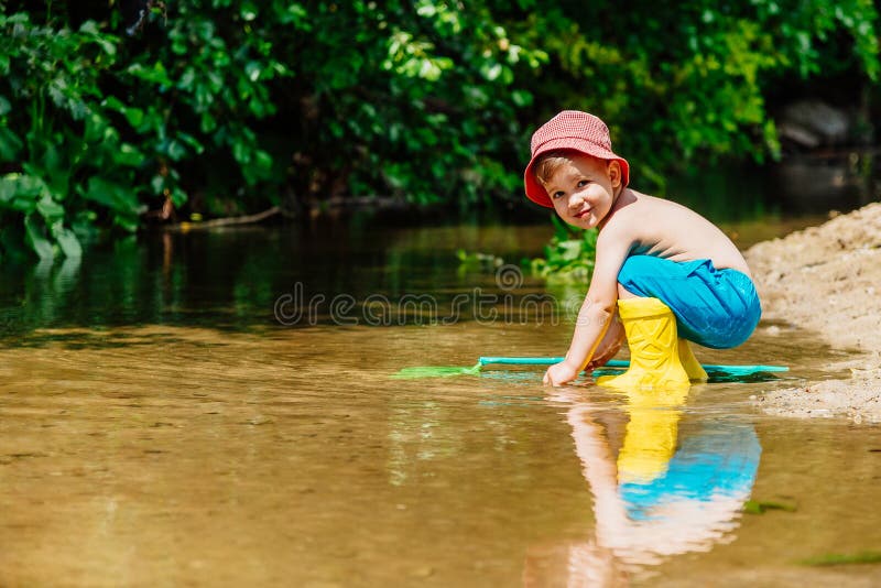 Mali dziecko chwyty ryba i żaby w rzece fotografia stock Mali dziecko chwyty ryba i żaby w rzece fotografia stock