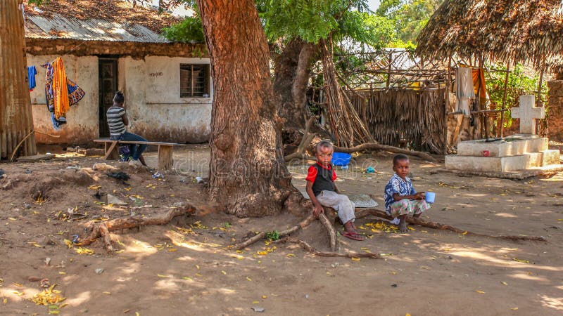 Malindi, Kenya - April 06, 2015: Unknown local kids sitting on tree root in front of their house. Living conditions in this area are generally poor. Malindi, Kenya - April 06, 2015: Unknown local kids sitting on tree root in front of their house. Living conditions in this area are generally poor.