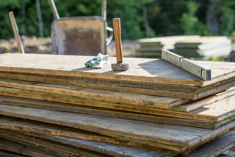 Mallet, protecting gloves and builders level on a pile of wooden stock photos